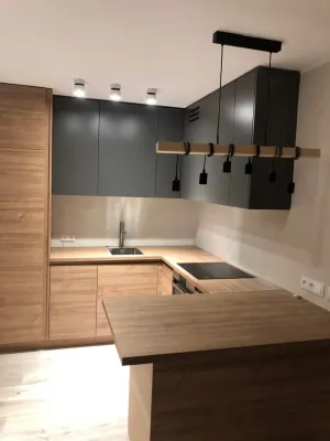 Model drewnianego domku na betonowym fundamencie leży na planach budowy obok miarki i ołówka, symbolizując koszt fundamentu.