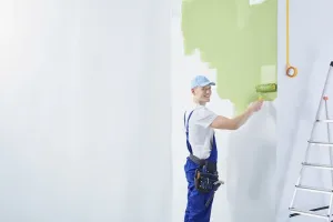 Słup ogrodzeniowy osadzony w wąskim wykopie z miarką i łopatką obok, pokazujący głębokość fundamentu pod ogrodzenie.