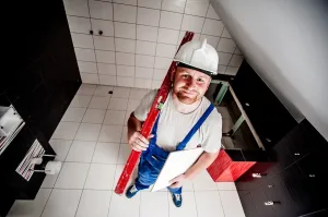 Ręce murarza porównujące pustak ceramiczny i bloczek z betonu komórkowego jako materiał na ściany domu